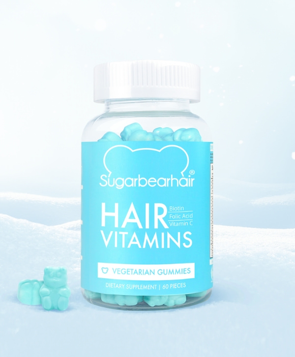 Une bouteille de vitamines capillaires SugarBearHair entourée de neige.