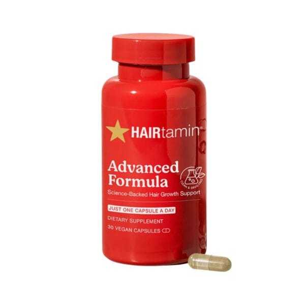 Un flacon rouge étiqueté "HAIRtamin - Vitamines Cheveux, 30 Capsules" avec une capsule beige à côté. Ce produit contient 30 gélules végétaliennes pour soutenir la croissance des cheveux.