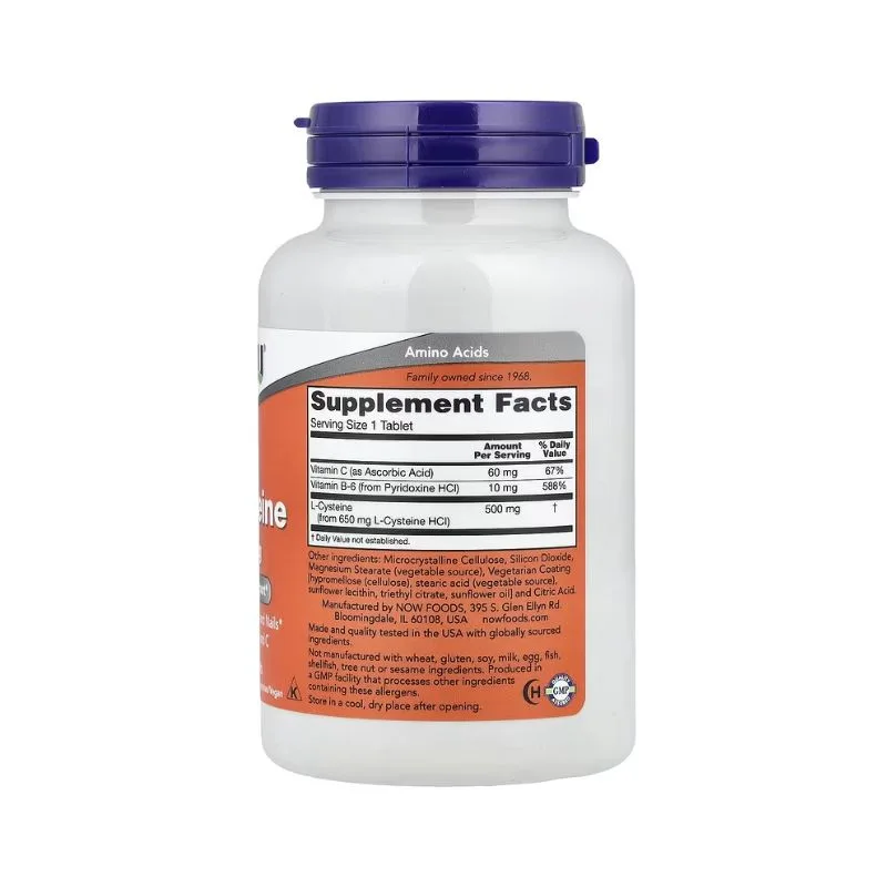 Une bouteille blanche de NOW Foods avec un bouchon violet affiche l'étiquette "L-Cystéine 500 mg - 100 comprimés", ainsi que des informations sur le supplément, les ingrédients et la posologie en texte noir et orange.